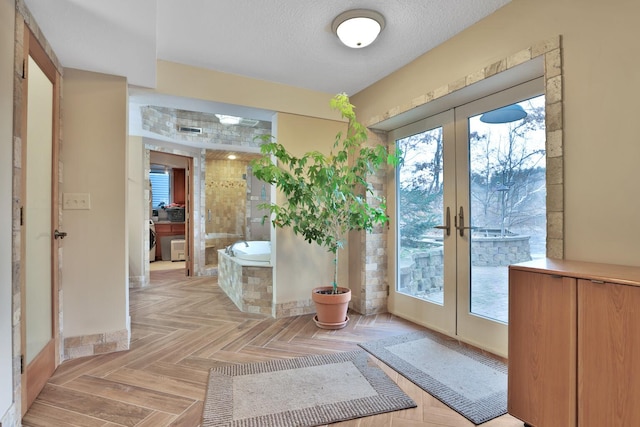 doorway featuring french doors, a wealth of natural light, a textured ceiling, and light parquet floors