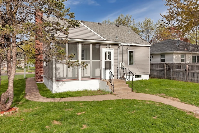 rear view of house with a yard and a sunroom