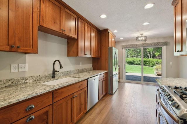 kitchen featuring light stone countertops, sink, light wood-type flooring, and appliances with stainless steel finishes