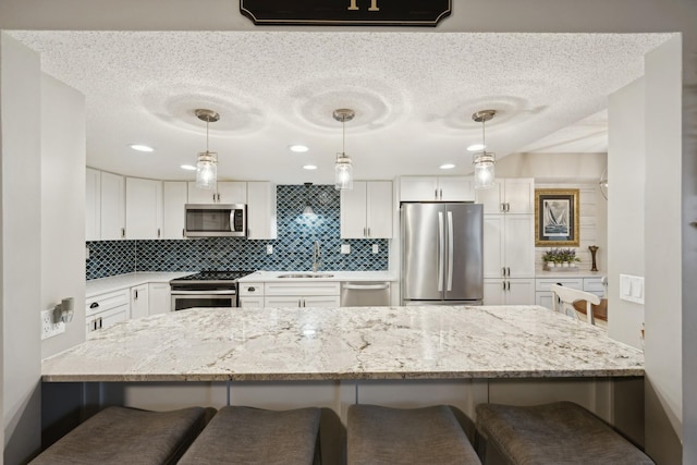 kitchen with a kitchen bar, kitchen peninsula, appliances with stainless steel finishes, backsplash, and white cabinets