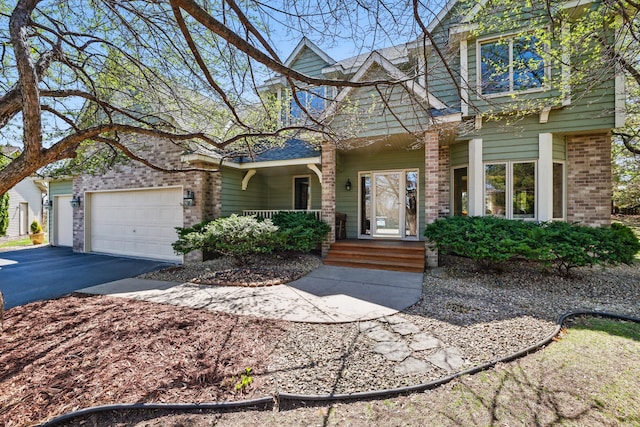 view of front of property featuring brick siding, a shingled roof, an attached garage, driveway, and a porch