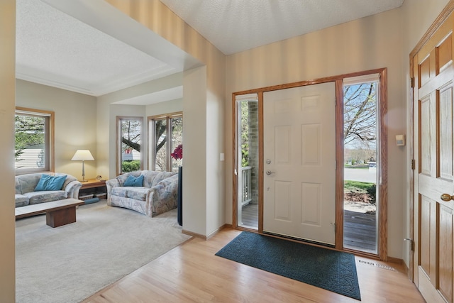 foyer with a textured ceiling, baseboards, and light wood finished floors