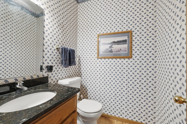 bathroom featuring vanity, toilet, and wallpapered walls