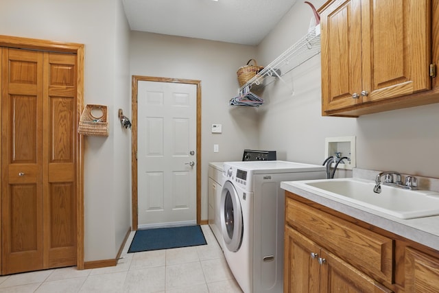 laundry room featuring light tile patterned flooring, baseboards, washing machine and clothes dryer, a sink, and cabinet space