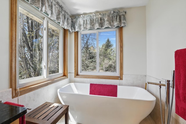 full bathroom with a wainscoted wall, a soaking tub, and tile walls