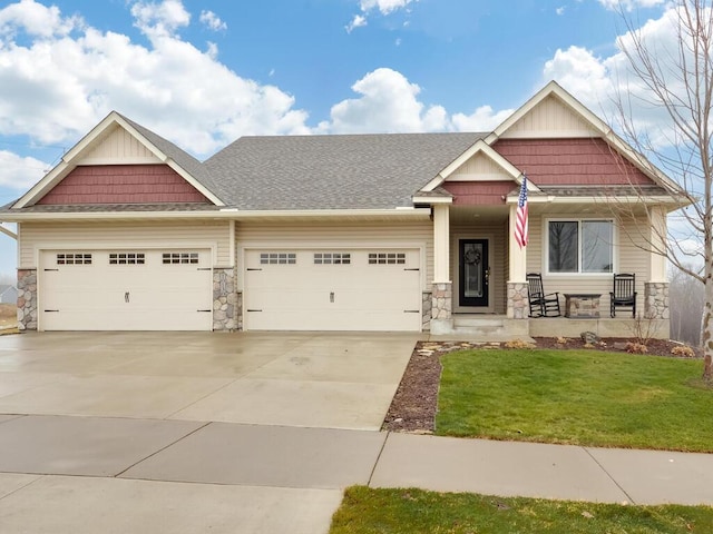 craftsman-style house featuring covered porch, a garage, and a front lawn