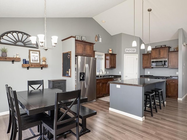 dining space with hardwood / wood-style flooring, sink, high vaulted ceiling, and a chandelier