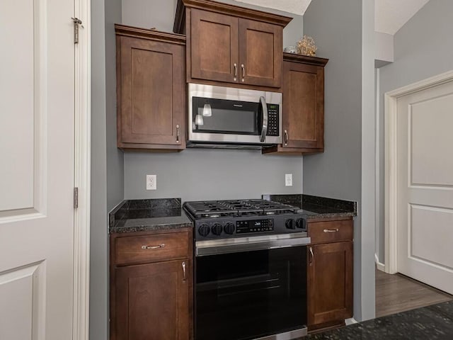 kitchen featuring dark hardwood / wood-style flooring, dark stone countertops, and stainless steel appliances