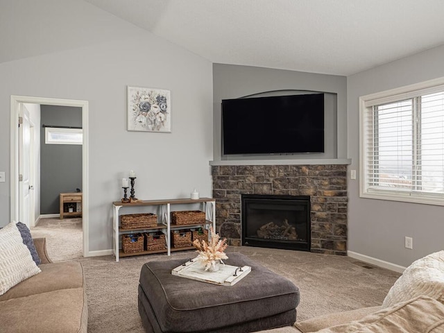 living room with a stone fireplace, light carpet, and vaulted ceiling