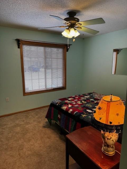 carpeted bedroom with ceiling fan and a textured ceiling