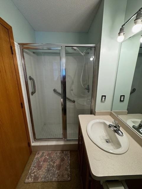 bathroom featuring tile patterned flooring, vanity, an enclosed shower, and a textured ceiling