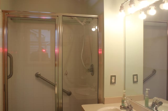 bathroom featuring a shower with door and sink