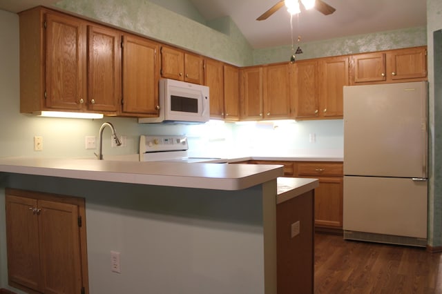 kitchen featuring white appliances, vaulted ceiling, ceiling fan, dark hardwood / wood-style flooring, and kitchen peninsula