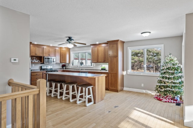 kitchen with a wealth of natural light, sink, stainless steel appliances, a kitchen breakfast bar, and a kitchen island