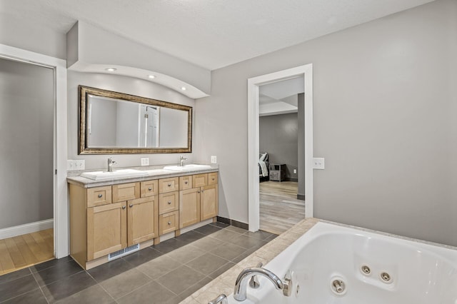 bathroom with a tub, tile patterned flooring, vanity, and a textured ceiling