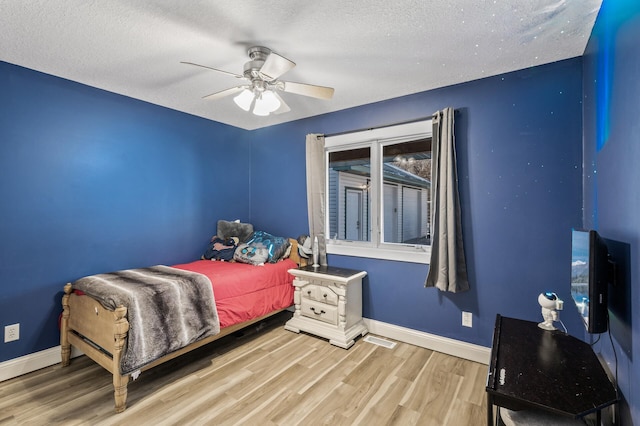 bedroom with ceiling fan, a textured ceiling, and hardwood / wood-style flooring