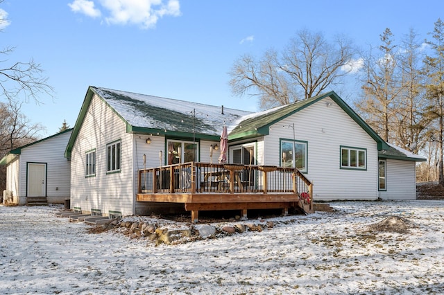 snow covered rear of property with a wooden deck