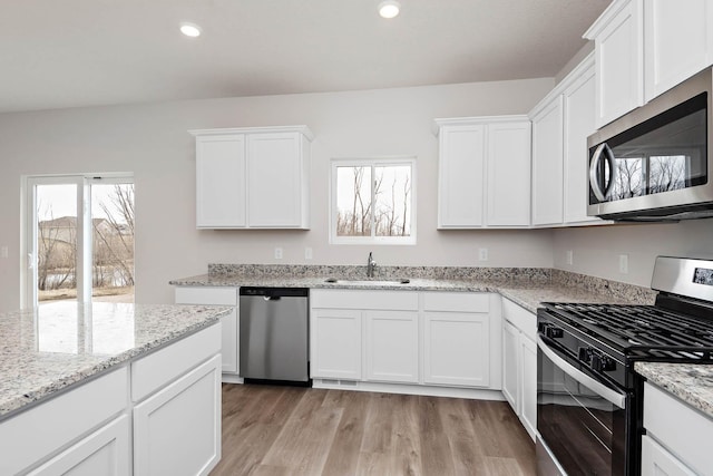 kitchen featuring light stone countertops, sink, light hardwood / wood-style flooring, white cabinets, and appliances with stainless steel finishes