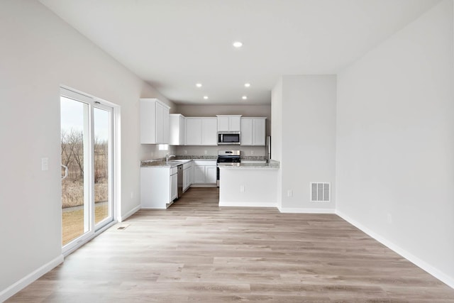 kitchen with white cabinets, a healthy amount of sunlight, light wood-type flooring, and stainless steel appliances