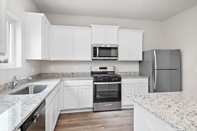 kitchen with white cabinets, appliances with stainless steel finishes, light hardwood / wood-style floors, and sink