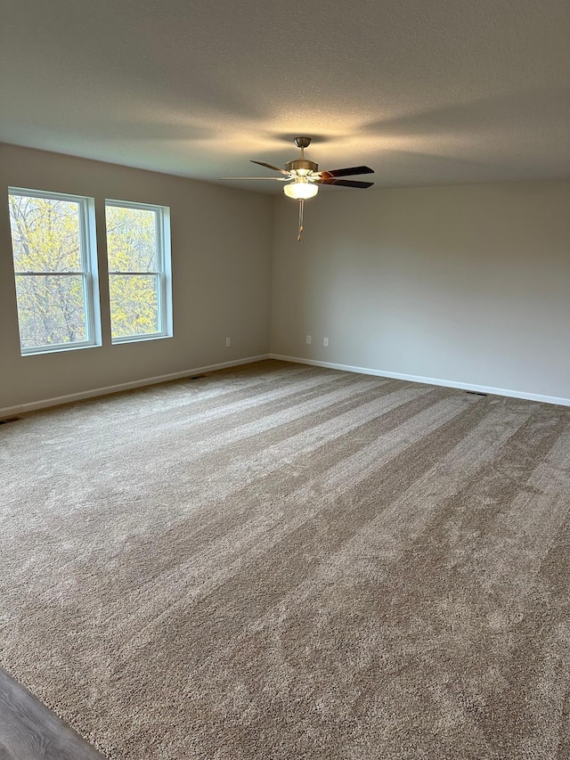 carpeted empty room with ceiling fan and a textured ceiling