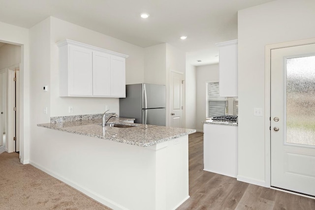 kitchen featuring kitchen peninsula, stainless steel fridge, and white cabinets