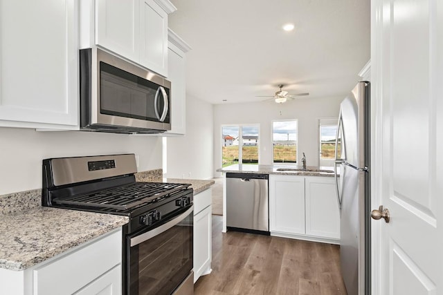 kitchen featuring white cabinetry, sink, stainless steel appliances, light stone counters, and light hardwood / wood-style flooring