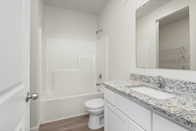 full bathroom featuring washtub / shower combination, hardwood / wood-style floors, vanity, and toilet