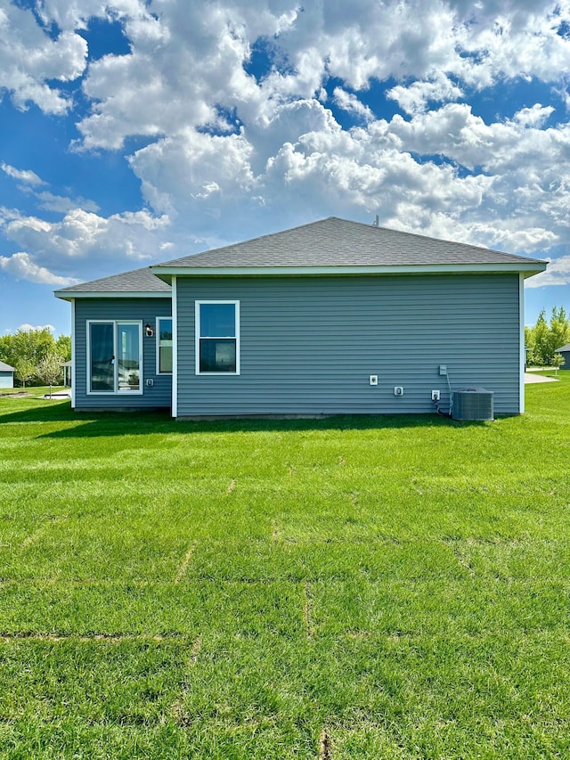 rear view of house with a lawn and central air condition unit