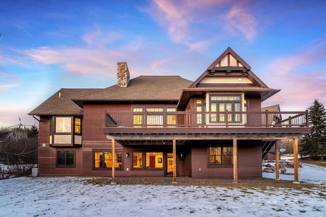 snow covered back of property with a wooden deck