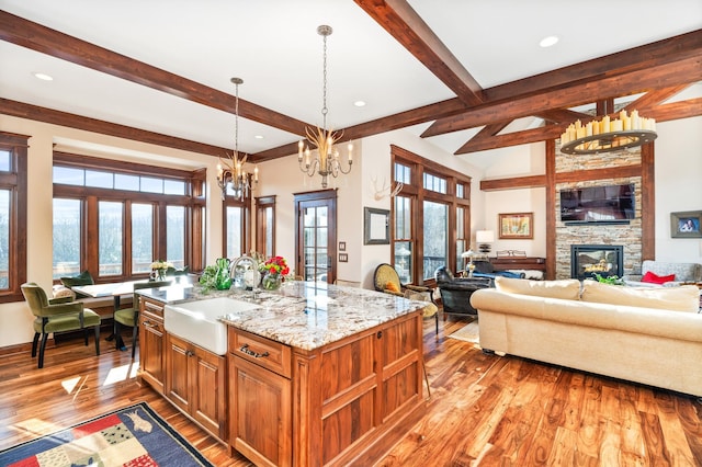 kitchen with decorative light fixtures, sink, an island with sink, and a wealth of natural light