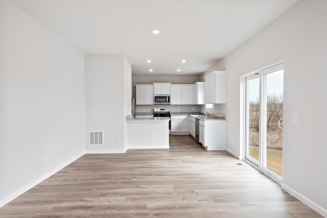 kitchen featuring white cabinets, light wood-type flooring, stainless steel appliances, and plenty of natural light