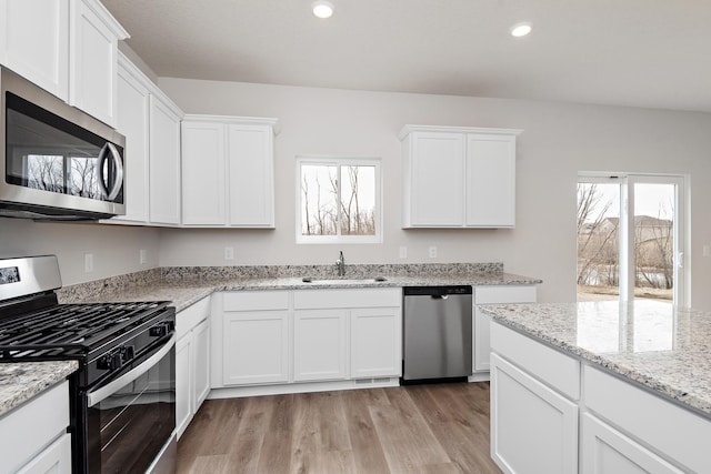 kitchen with appliances with stainless steel finishes, light hardwood / wood-style flooring, white cabinetry, and sink