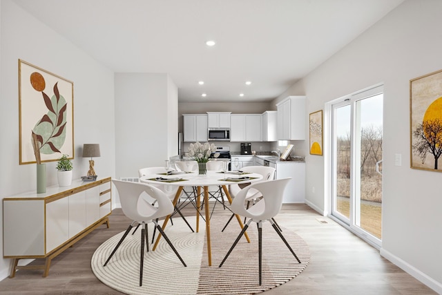 dining area with baseboards, light wood-type flooring, and recessed lighting