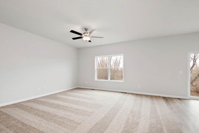 empty room with light wood-type flooring, ceiling fan, visible vents, and baseboards