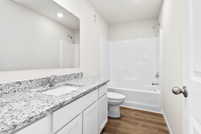 bathroom featuring toilet, wood finished floors, vanity, bathing tub / shower combination, and baseboards