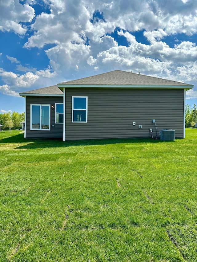 rear view of property featuring a lawn and central AC unit