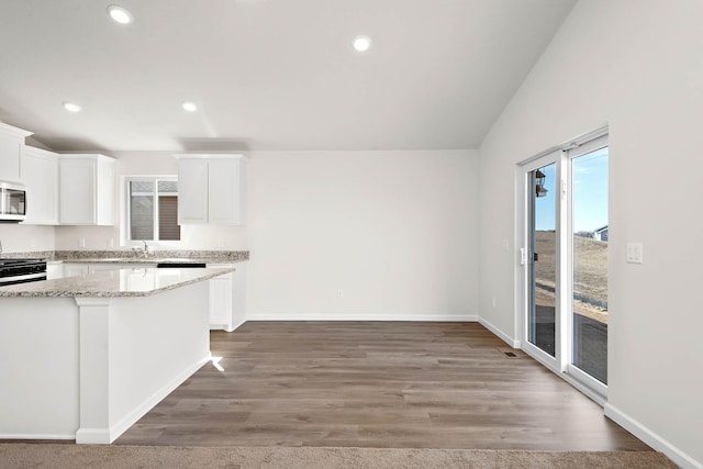 kitchen with white cabinetry, wood-type flooring, and lofted ceiling