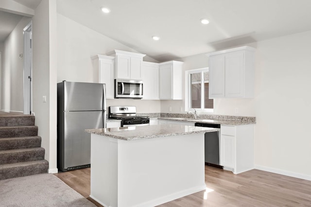 kitchen with white cabinets, light wood-type flooring, lofted ceiling, and appliances with stainless steel finishes