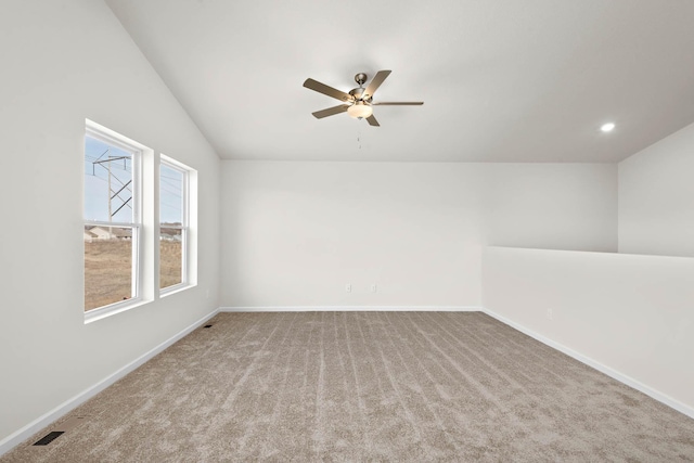 carpeted spare room with ceiling fan and vaulted ceiling