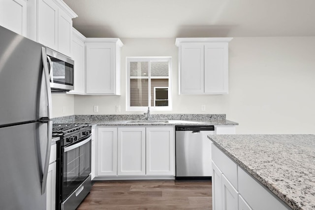 kitchen with light stone countertops, stainless steel appliances, sink, dark hardwood / wood-style floors, and white cabinetry