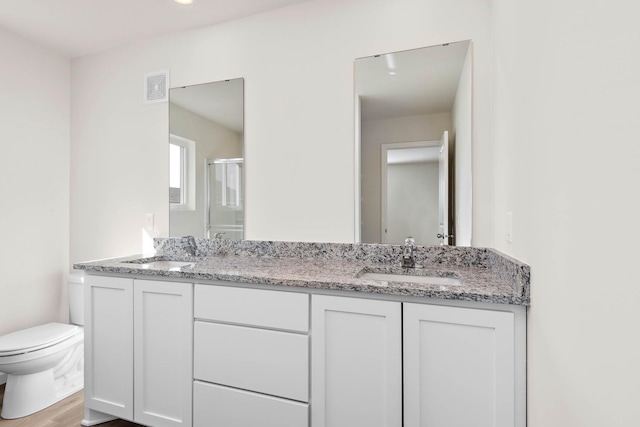 bathroom featuring hardwood / wood-style flooring, vanity, toilet, and a shower with shower door