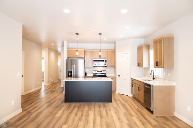 kitchen featuring sink, light hardwood / wood-style floors, decorative light fixtures, a kitchen island, and stainless steel appliances