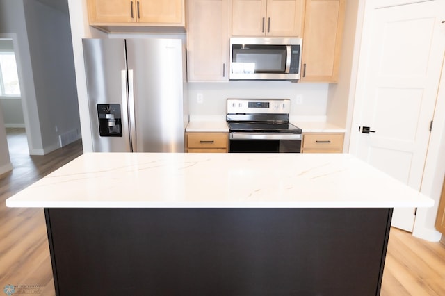 kitchen with light brown cabinets, light hardwood / wood-style floors, and appliances with stainless steel finishes