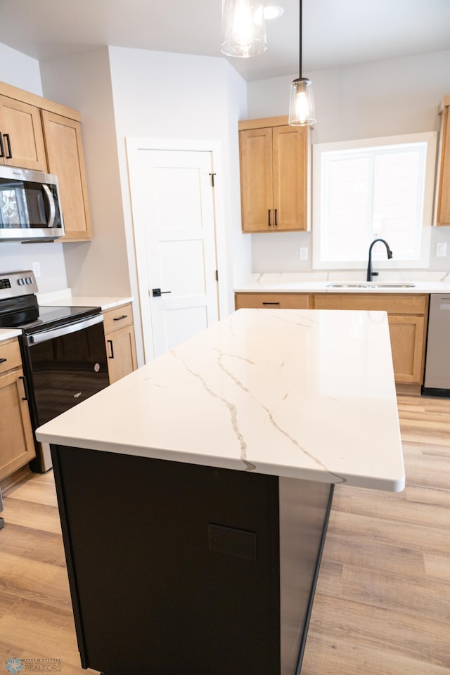 kitchen with light wood-type flooring, stainless steel appliances, sink, a kitchen island, and hanging light fixtures