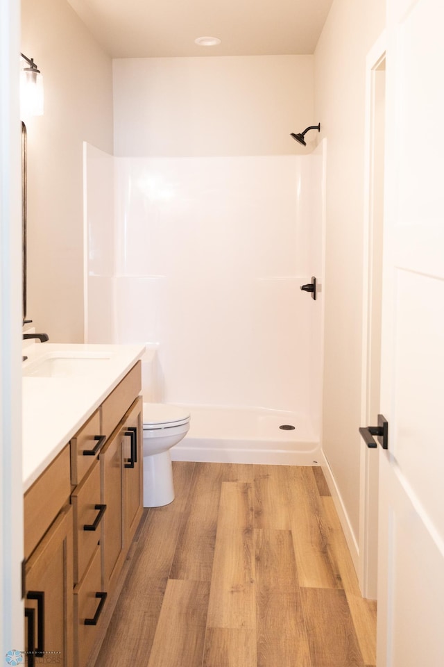 bathroom with a shower, toilet, vanity, and hardwood / wood-style flooring