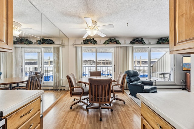 dining area with a textured ceiling, ceiling fan, and light hardwood / wood-style floors