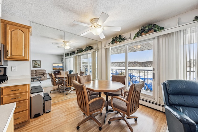 dining area featuring baseboard heating, ceiling fan, a textured ceiling, and light hardwood / wood-style flooring