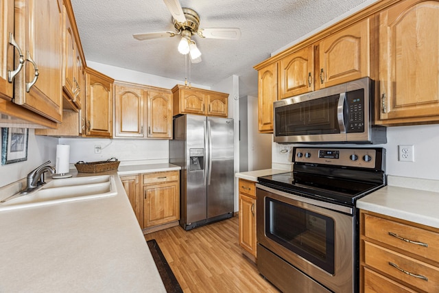 kitchen featuring light hardwood / wood-style floors, stainless steel appliances, a textured ceiling, ceiling fan, and sink