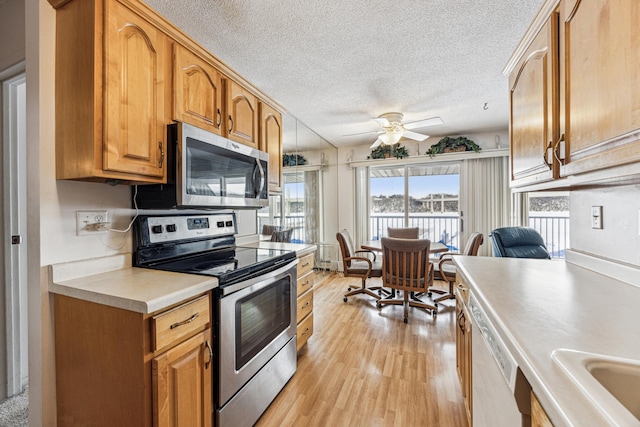 kitchen featuring sink, a textured ceiling, ceiling fan, light hardwood / wood-style floors, and appliances with stainless steel finishes